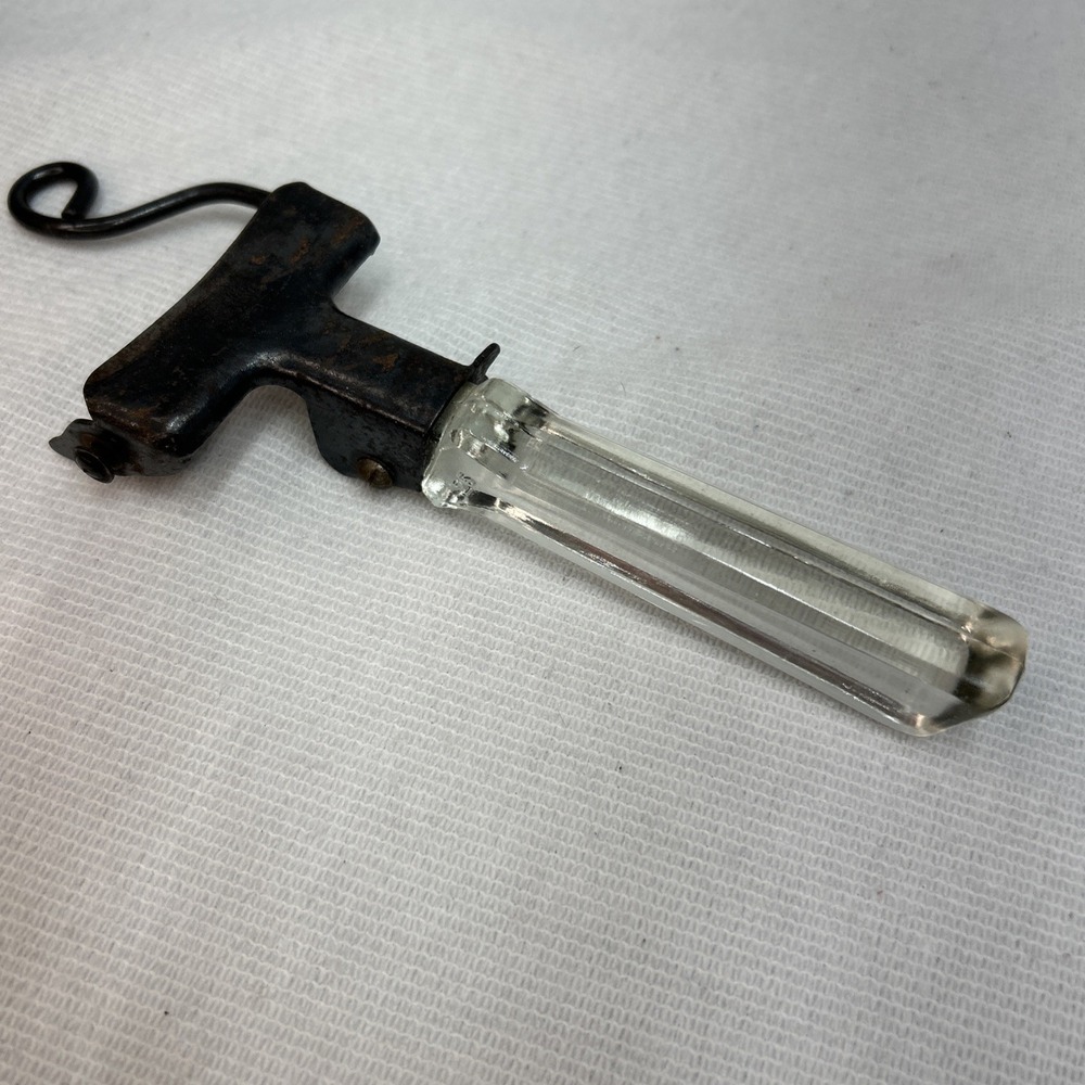 Vintage Pyrex pot lid lifter tool with a glass handle.